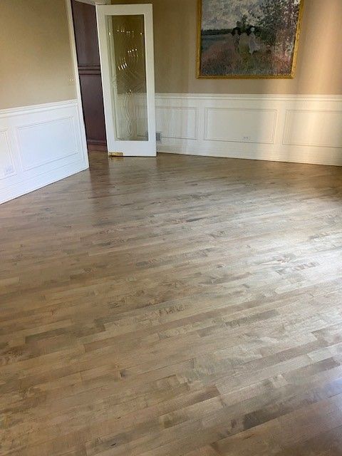 a living room with hardwood floors and a painting on the wall