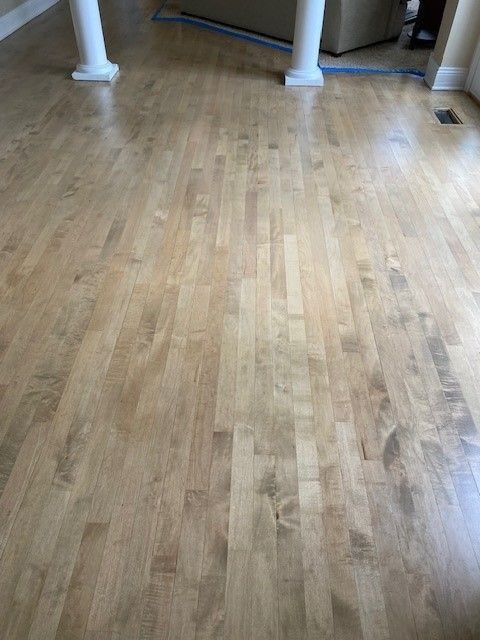 a wooden floor in a living room with columns and a couch.