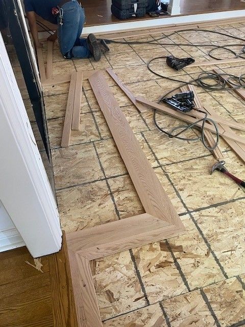 a man is kneeling on the floor while cutting wood.