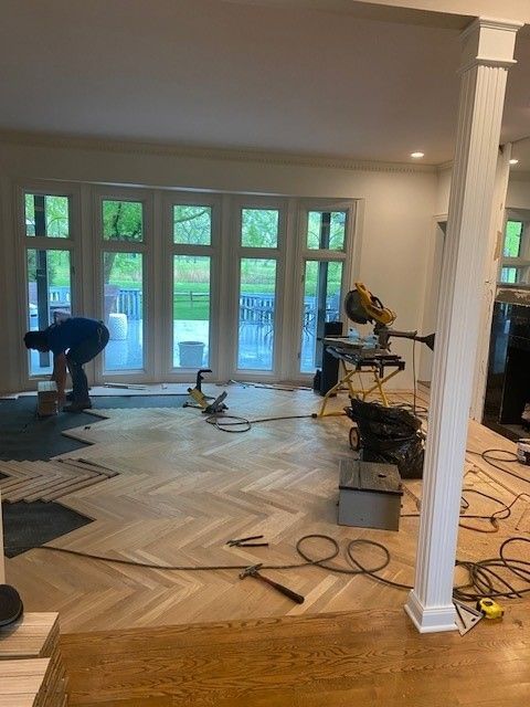 a man is working on a wooden floor in a living room.