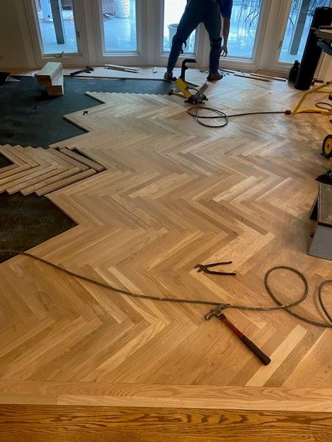 a man is installing a herringbone wooden floor in a living room.