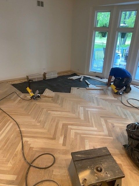 a man is working on a wooden floor in a room.