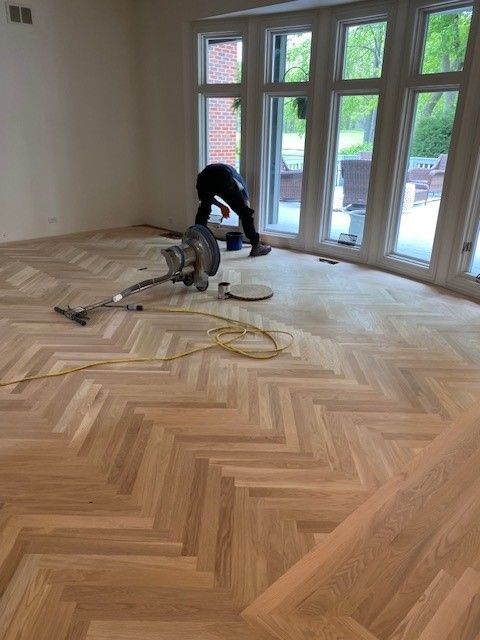 a man is sanding a wooden floor with a vacuum cleaner.