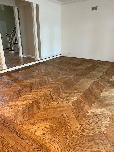 a living room with a herringbone wood floor and white walls.