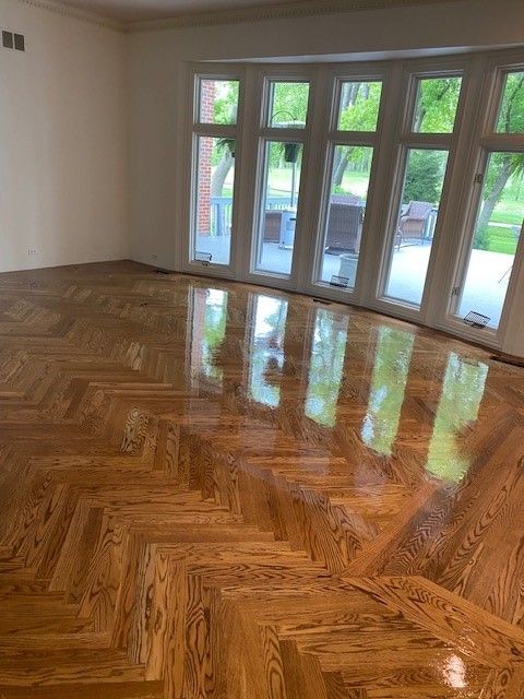 a living room with a wooden floor and lots of windows.