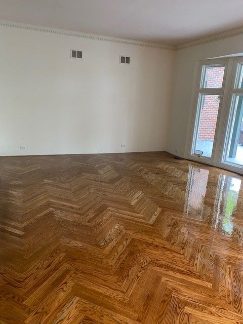 an empty living room with a herringbone wood floor and white walls.