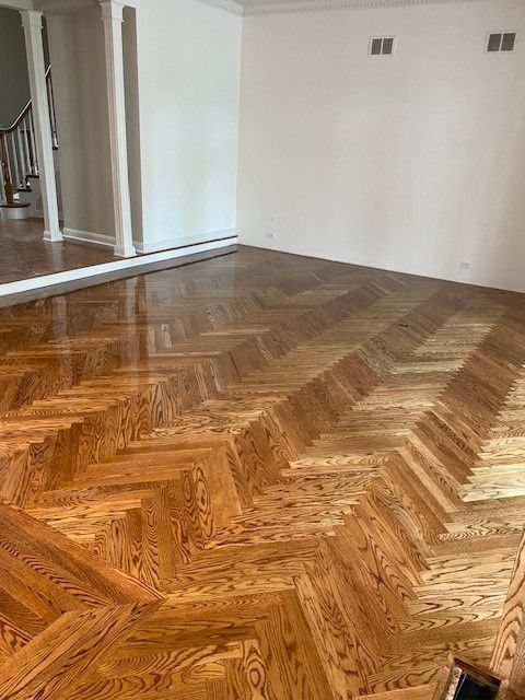 a living room with a wooden floor in a herringbone pattern.