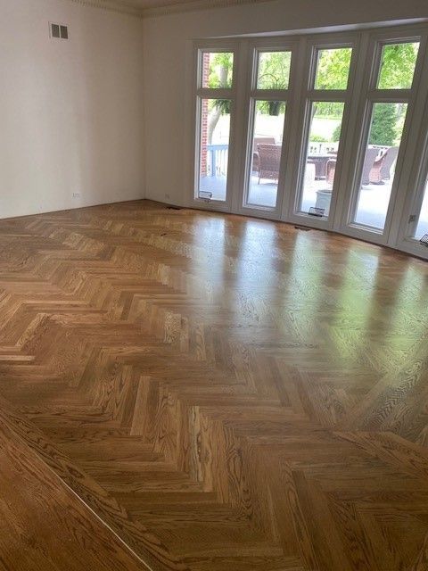 a living room with a wooden floor and lots of windows.