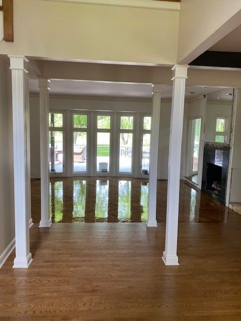 a large empty room with hardwood floors and white pillars