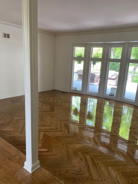 a living room with a wooden floor and lots of windows.