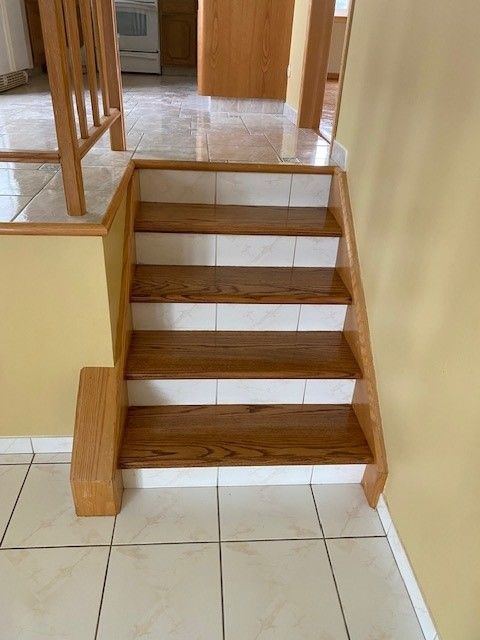 a wooden staircase with white tile steps in a house.