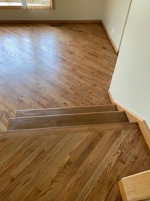 a wooden floor with stairs leading up to it in a living room.