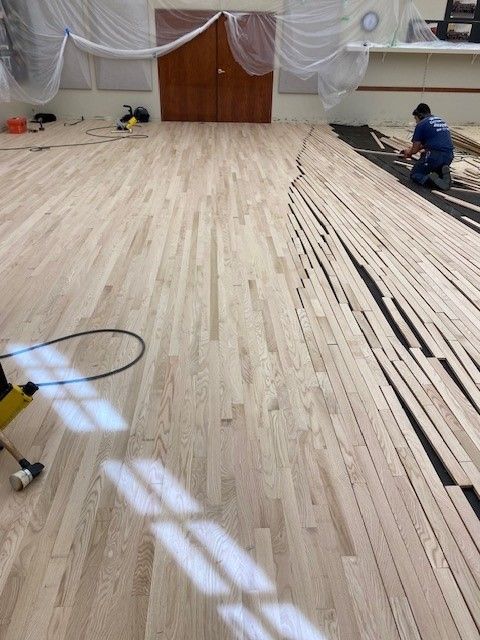 a man is working on a wooden floor in a room 