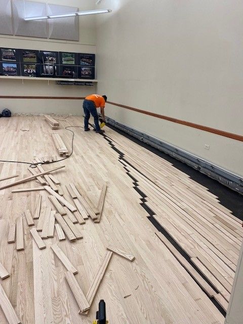 a man is working on a wooden floor in a room