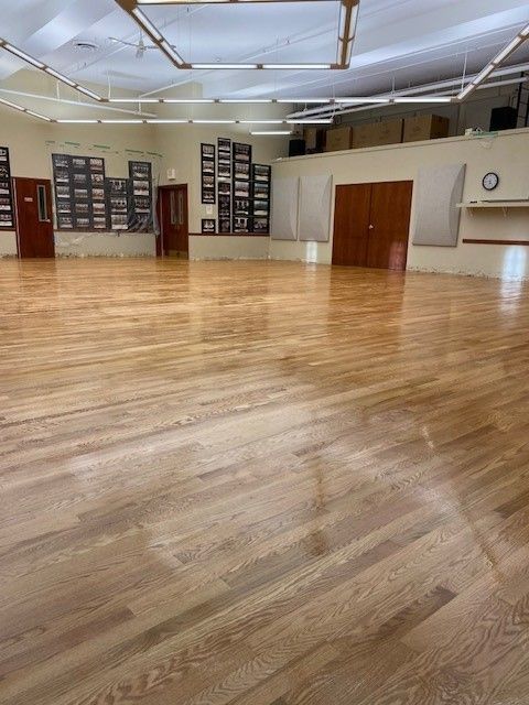 a large empty dance studio with wooden floors and doors.