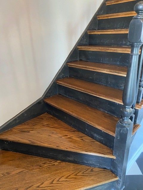 a close-up of a wooden staircase with a black railing.