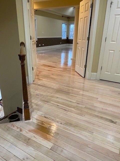 a wooden floor in a house with a staircase and a door 