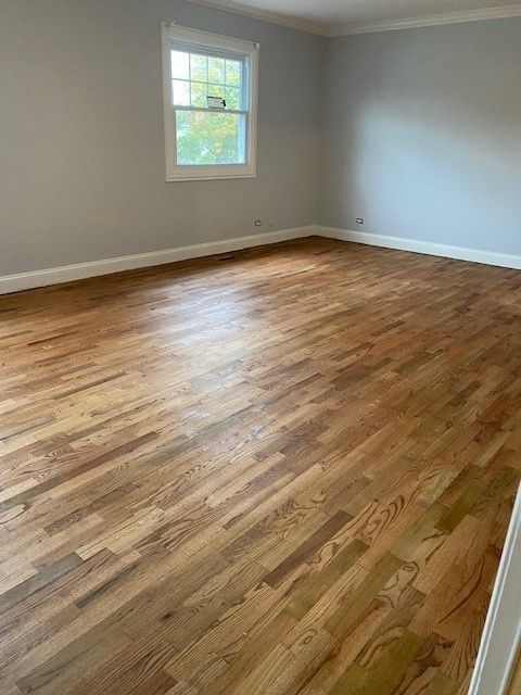an empty living room with hardwood floors and a window.