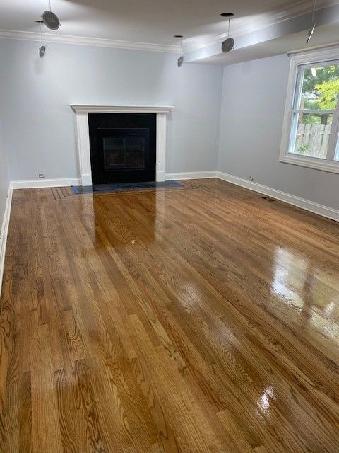 an empty living room with hardwood floors and a fireplace.