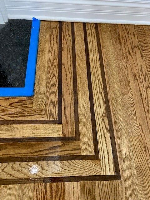 a close-up of a wooden floor with a blue tape on it.