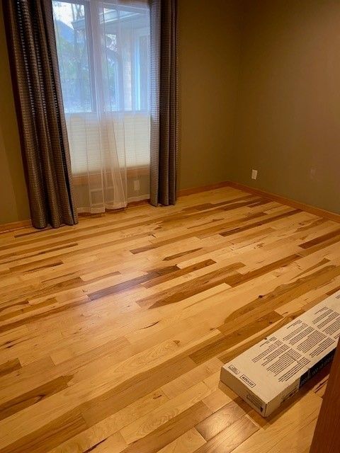 a bedroom with hardwood floors and a window.
