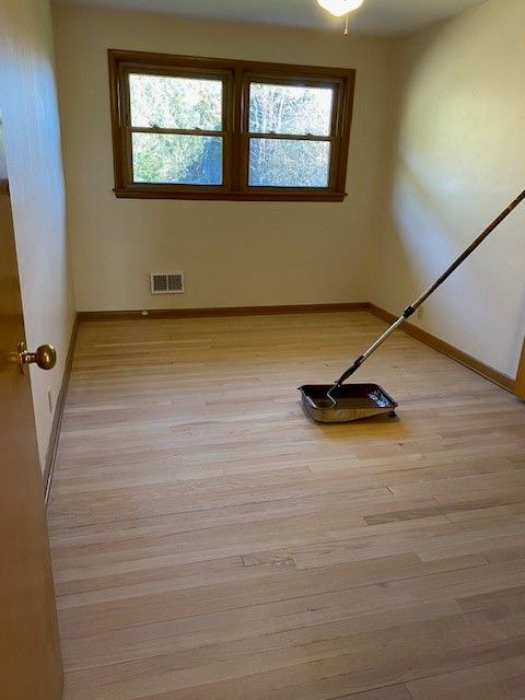 an empty room with a broom on the floor and a window.