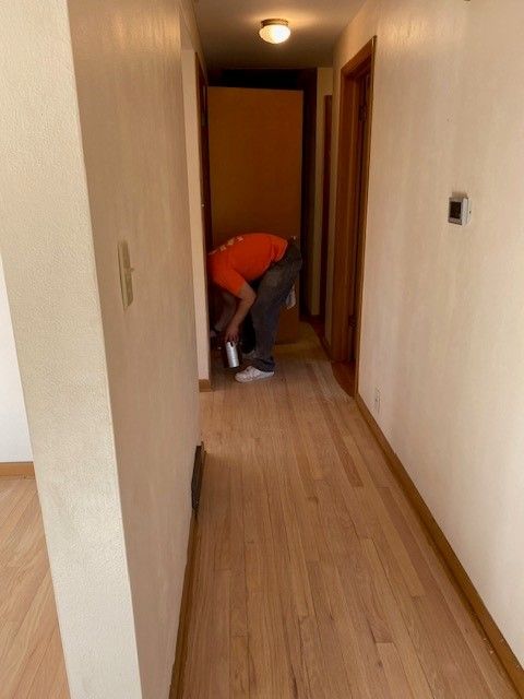 a man in an orange shirt is bending down in a hallway