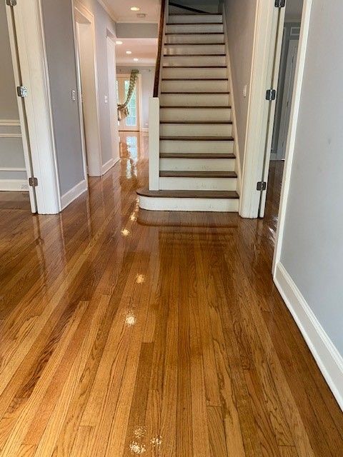 a hallway with hardwood floors and stairs in a house.