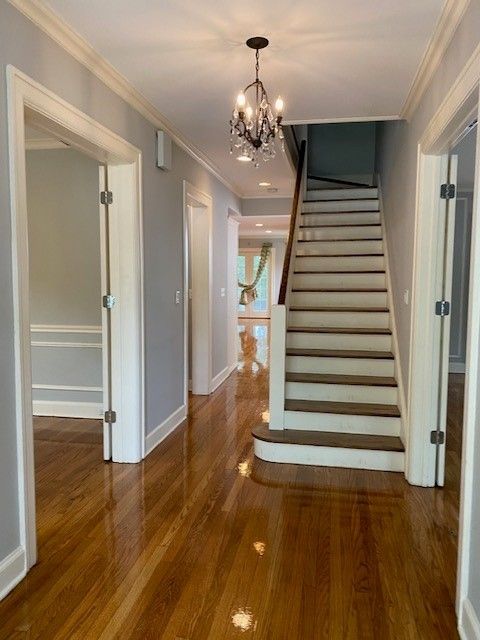 a hallway with stairs and a chandelier hanging from the ceiling