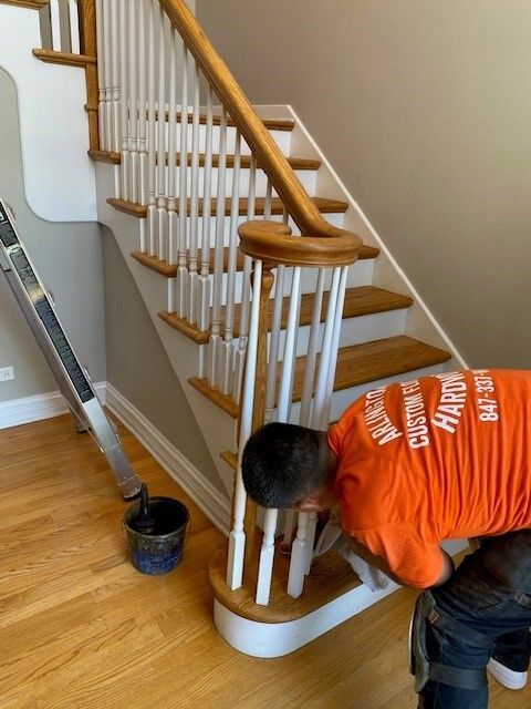a man in an orange shirt is painting a staircase