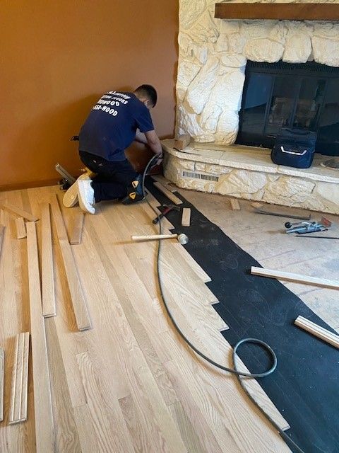 a man is working on a wooden floor in a living room.