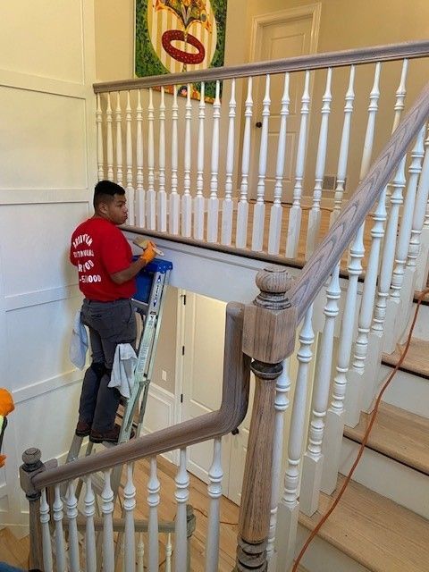 a man in a red shirt is standing on a ladder on a staircase