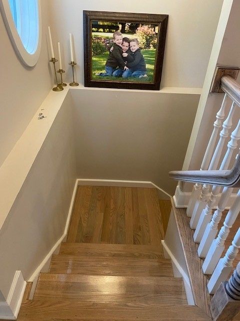a picture of a family is hanging on the wall above the stairs 