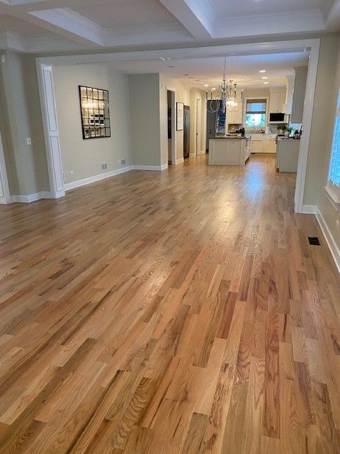a living room with hardwood floors and a kitchen in the background.