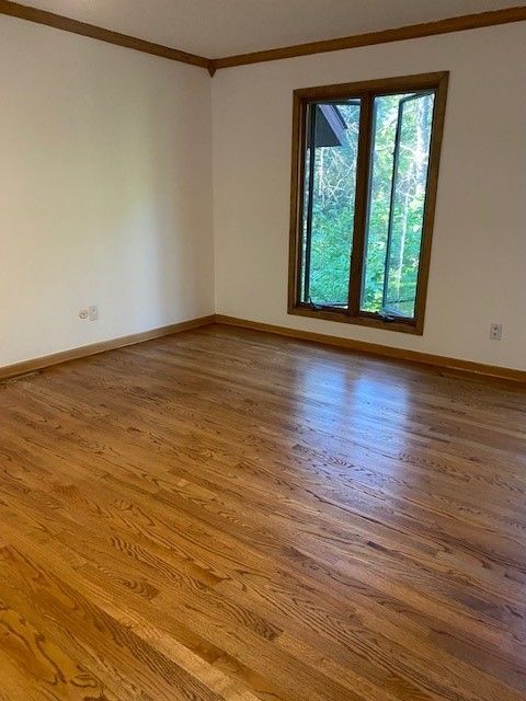 an empty room with hardwood floors and a window