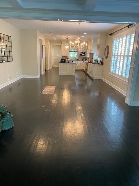 a living room with hardwood floors and a kitchen in the background.