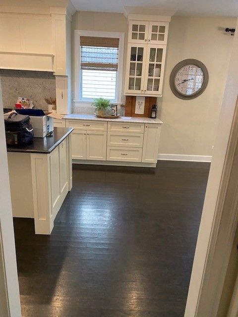 a kitchen with white cabinets and a clock on the wall.