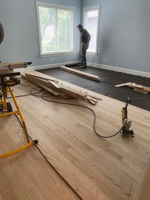 a man is working on a wooden floor in a room.