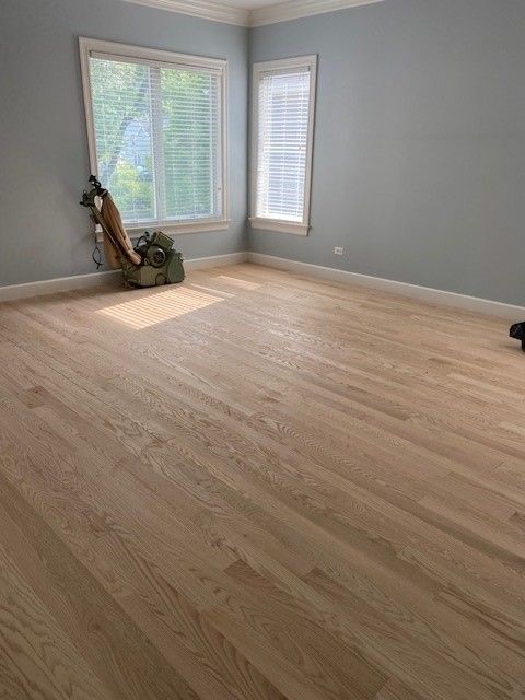 a large empty room with hardwood floors and two windows.