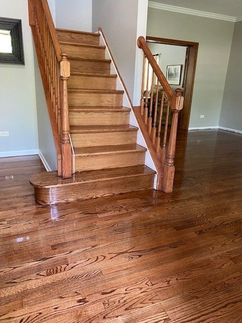 a wooden staircase in a living room with hardwood floors.