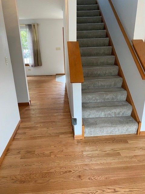 a staircase with a wooden railing and carpeted steps in a house.