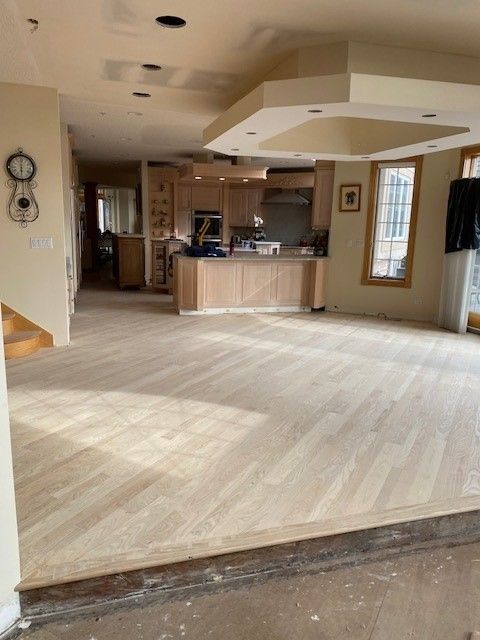a large room with a wooden floor and a kitchen in the background