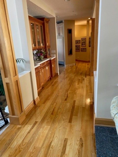 a hallway with hardwood floors and cabinets in a house.