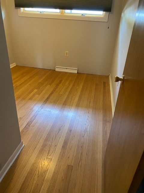 an empty room with hardwood floors and a window.