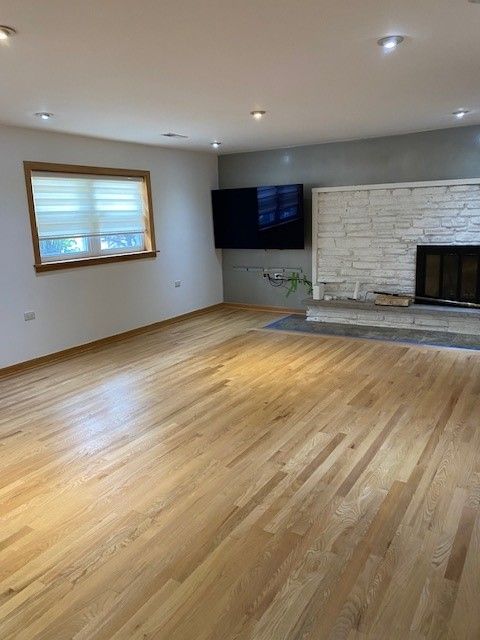 a living room with hardwood floors, a fireplace, and a flat-screen tv.