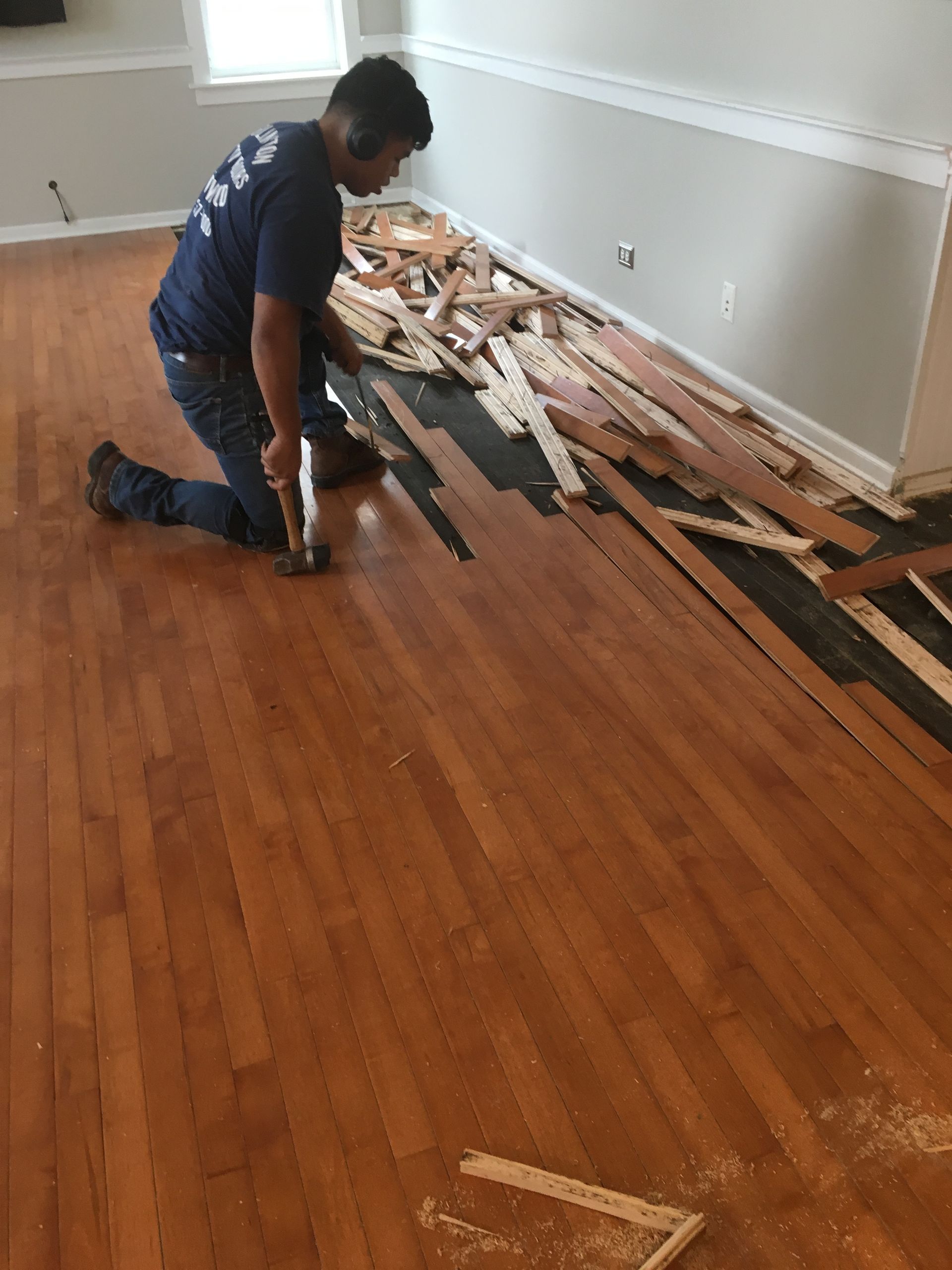 a man is kneeling on the floor in a living room with a hammer.