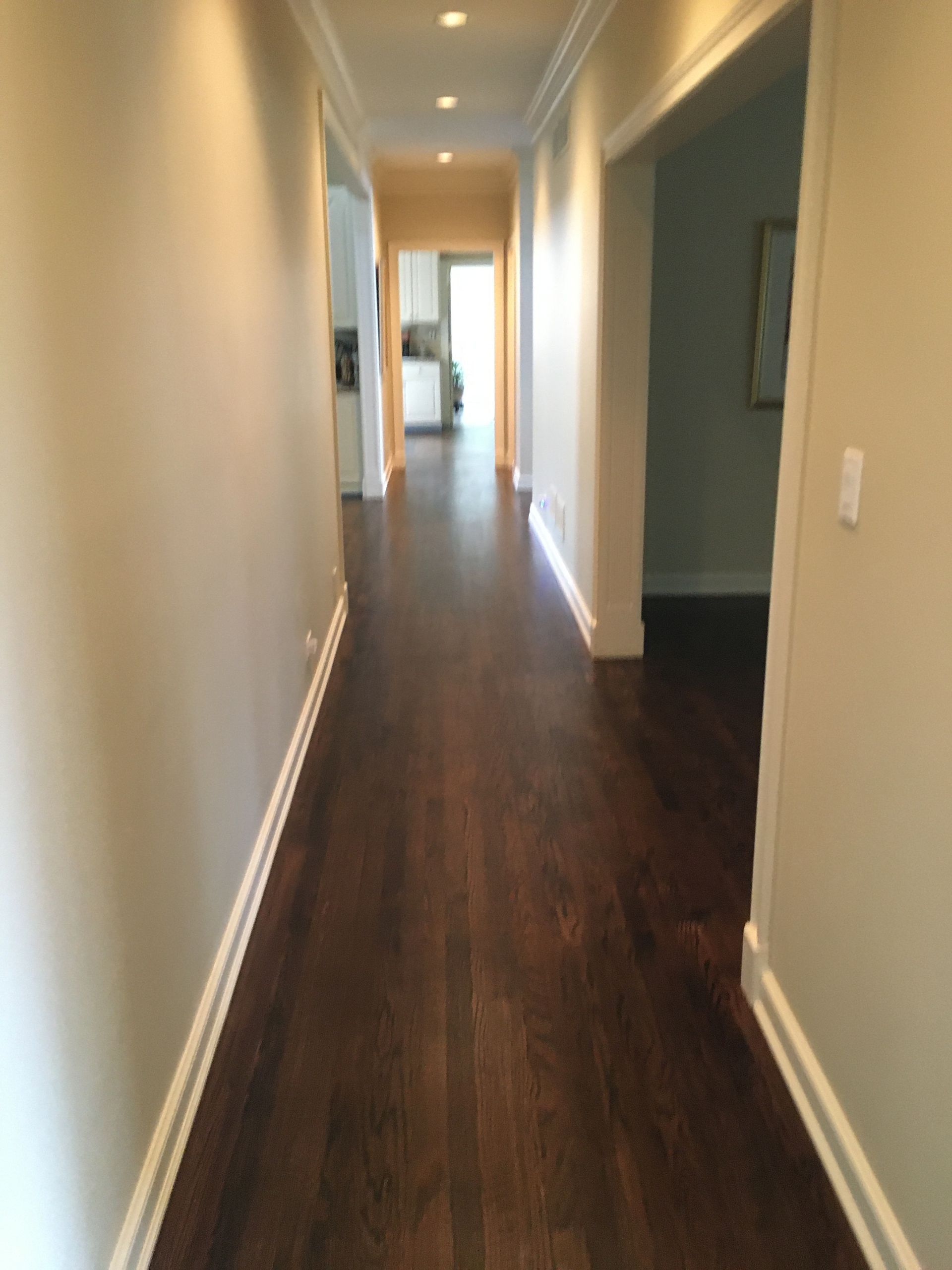 a long hallway with hardwood floors and white trim