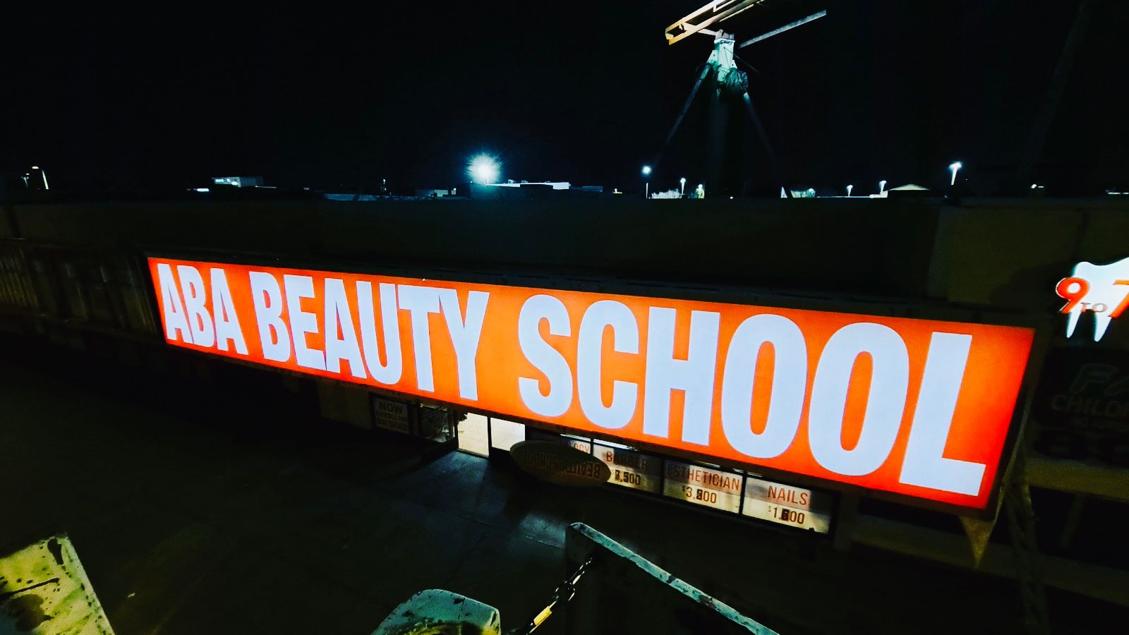 A beauty school sign is lit up at night