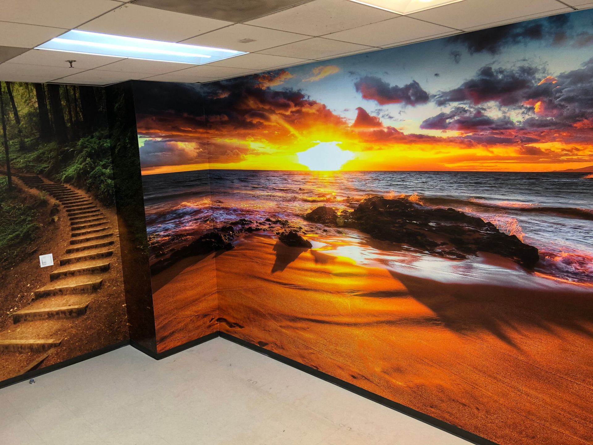 A wall with a picture of a sunset over the ocean