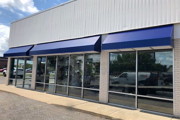 A white building with blue awnings on the windows.